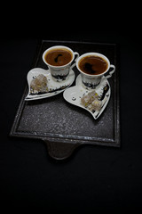 traditional Turkish coffee with Turkish delight. heart shaped saucers and traditional Turkish coffee on black granite   tray in black background. Coffee cups and saucers with the symbols of istanbul.