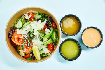 Salad with salmon and cherry tomatoes, lemon, avocado, cucumber, lettuce, arugula, Parmesan cheese, a sprig of rosemary in a cardboard box