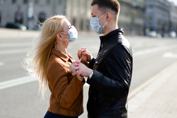 Young couple in masks on city street.