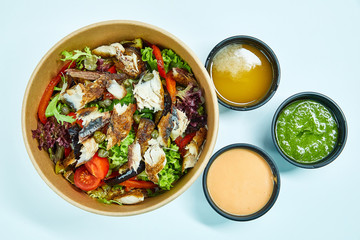 Sea fish salad with cherry tomatoes, capers, grilled vegetables, lettuce in a cardboard box