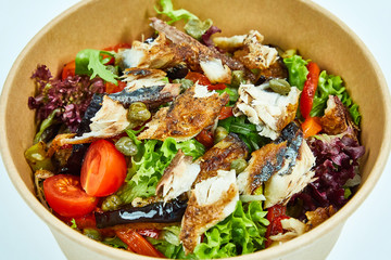 Sea fish salad with cherry tomatoes, capers, grilled vegetables, lettuce in a cardboard box