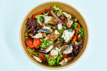 Sea fish salad with cherry tomatoes, capers, grilled vegetables, lettuce in a cardboard box