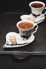 traditional Turkish coffee with Turkish delight. heart shaped saucers and traditional Turkish coffee on black granite   tray in black background. Coffee cups and saucers with the symbols of istanbul.