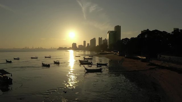 Beautiful flight over boats in Penang Malaysia. The drone video was taken when the sun was rising. The video shows the sea and the city with skyscrapers in Penang.