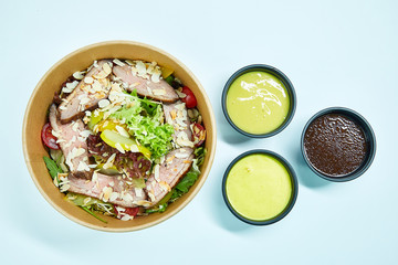 Salad with grilled duck and cherry tomatoes, pear, lettuce, arugula, almonds in a cardboard box