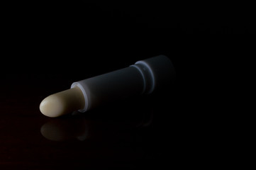 cocoa butter lipstick gloss, to moisturize chapped lips, on cold winter days. Concept photo with dramatic light, copy text space and black background