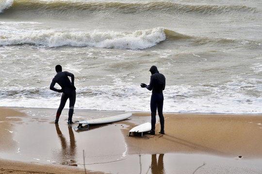 Young adults surfers wearing wetsuit warming up on beach preparing. 