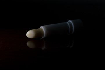 cocoa butter lipstick gloss, to moisturize chapped lips, on cold winter days. Concept photo with dramatic light, copy text space and black background