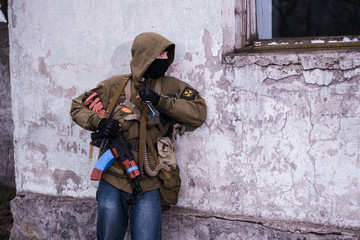 Fototapeta na wymiar Rebel with AK and bayonet knife looking to window
