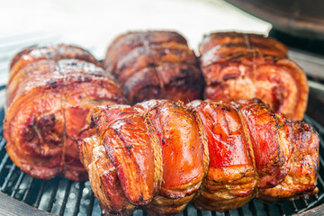 Fresh, delicious grilled porchetta. Grilling porchetta on BBQ. Closeup of a porchetta on a grill, detail on the crunchy skin