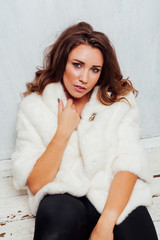 portrait of a beautiful fashionable woman with hair curls in a white fur coat
