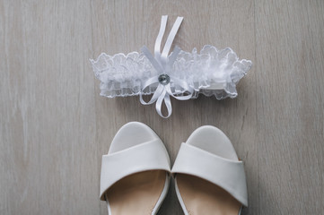 White garter, women's wedding white, cream shoes close-up. Morning and preparation of the bride. Photography, concept.