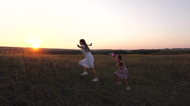 healthy Children in meadow with an airplane in his hand. Dreams of flying. concept of happy childhood. Two free girls play with a toy airplane on field. Silhouette of children playing on an airplane.