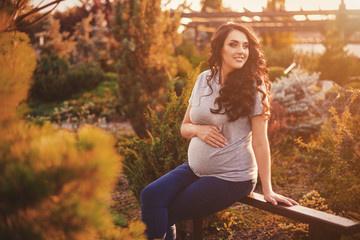 Beautiful pregnant woman in the garden at summer sunset