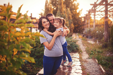 Portrait Of Happy Family In Garden. family expecting a second child