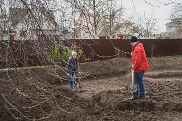 A man with children digs the ground with a shovel in the spring. Do-it-yourself pond