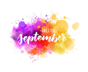 Hello September -  handwritten modern calligraphy lettering on abstract watercolor imitation splash. Purple, pink and yellow colored. Painted background.