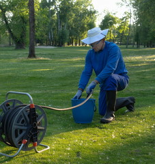Worker fills water into a bucket image,maintaining the greenery