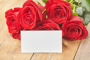 Blank card with red rose on a wooden background Close up