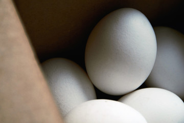 White oval-shaped chicken eggs in a brown box in the daytime close-up. The concept of agricultural production