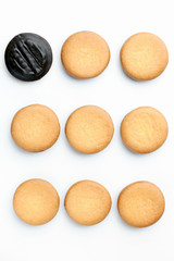 Round shortbread and one piece covered in chocolate in a row on a white vertical background in the top view. The concept of making homemade pastry and dessert