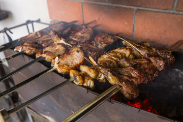 Shashlik or shashlyk cooked on metal skewers over charcoal. Grilled chicken wings, pork ribs, steaks with bones,  on metal skewers. Mix of several types of meat is roasted on fire at outside kitchen.