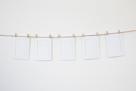 marcos de fotos blancos de papel colgados con pinzas de madera