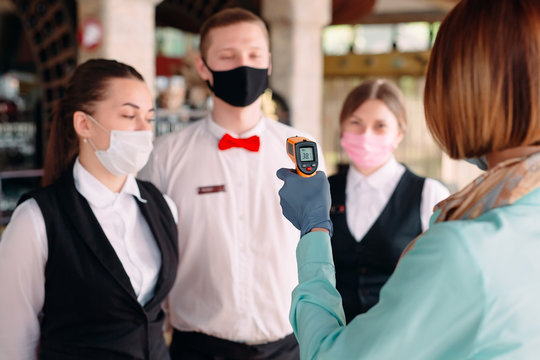 The Manager of a restaurant or hotel checks the body temperature of the staff with a thermal imaging device.