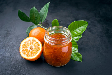 Fresh bitter orange marmalade with ripe fruit offered as closeup on a rustic black board with copy space