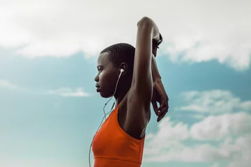 Foto op Canvas African woman with earphones doing stretching exercise © Jacob Lund
