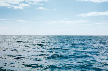 Obraz premium Blue sea with waves and blue cloudy sky