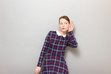 Portrait of young woman placing hand near ear and eavesdropping