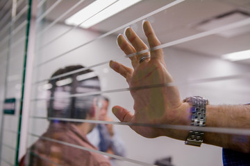 Close up of hands of conversation participant against glass wall listening and waiting.