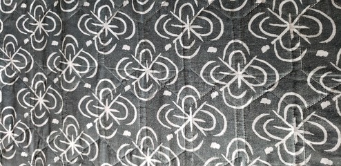 Fototapeta premium Abstract, black and white floral pattern repeating across a quilt. 
