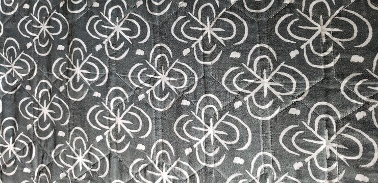 Abstract, black and white floral pattern repeating across a quilt. 