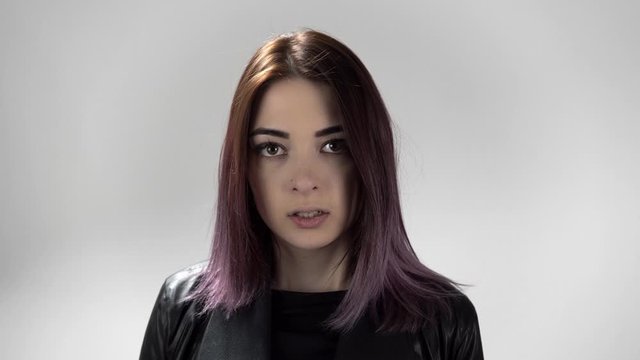 Portrait of young attractive woman with violet hair showing different emotions. The girl shows laugh, anger, surprise, hate standing in the studio. Concept of showing different facial expressions.