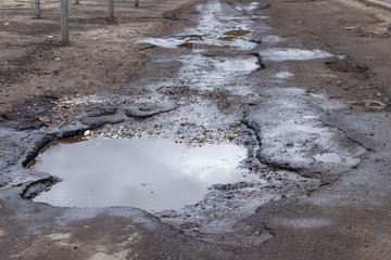 Bad asphalt road with pit and puddle.