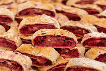Puff pastry, fresh baked strudel cut into pieces, strudel with apples and berries, and sprinkled with powdered sugar , pastry product, pieces of strudel closeup. Street food market