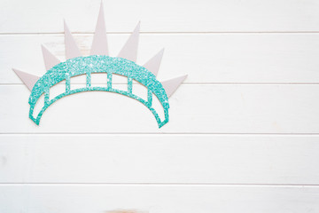 Statue of liberty crown on white wooden table with copy space