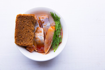 Herring in tomato sauce in a plate, brown bread and dill
