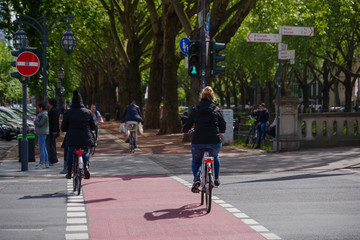 People or cyclists ride bicycle on the bicycle lanes cross at pedestrian crossing at Königsallee in Düsseldorf, Germany. Urban Eco friendly lifestyle transportation.	
