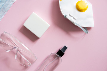 Medical protective mask, respirator ffp, soap, rubber gloves, antiseptic and protective glasses lie on a pink background. Anti-virus protection kit against covid-19. Coronavirus pandemic 2019.