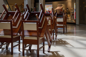 Selected focus at stack of chairs at dining area of restaurant in shopping mall which closed during during epidemic of COVID-19 virus. COVID-19 restrictions on restaurant in Europe.