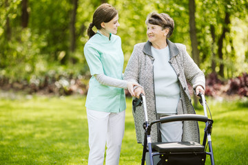 Senior disabled woman with caregiver in the garden of the nursing home