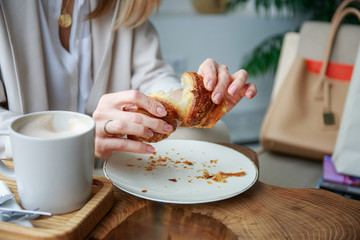 The girl breaks a croissant with her hands
