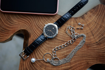 Watch, jewelry, phone on a wooden table
