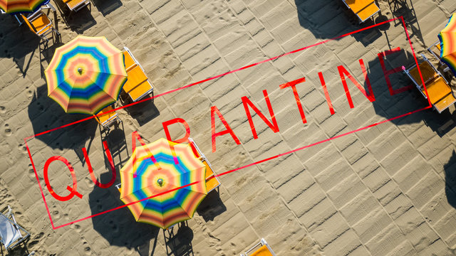 Bird's eye view of a beach aligned with umbrellas, overimpressed the text quarantine, due to  covid pandemia the touristic season is severely at risk in mnay country around the world.