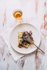 Meat fillet with grilled zucchini on a white dish with a glass of beer,  napkin and golden fork, backlighted image on a rustic top white board