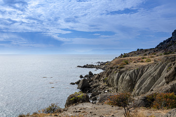 Seascape, sky, mountains, sea, large stones on the coast.