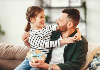 Cute girl hugging happy father with gift.